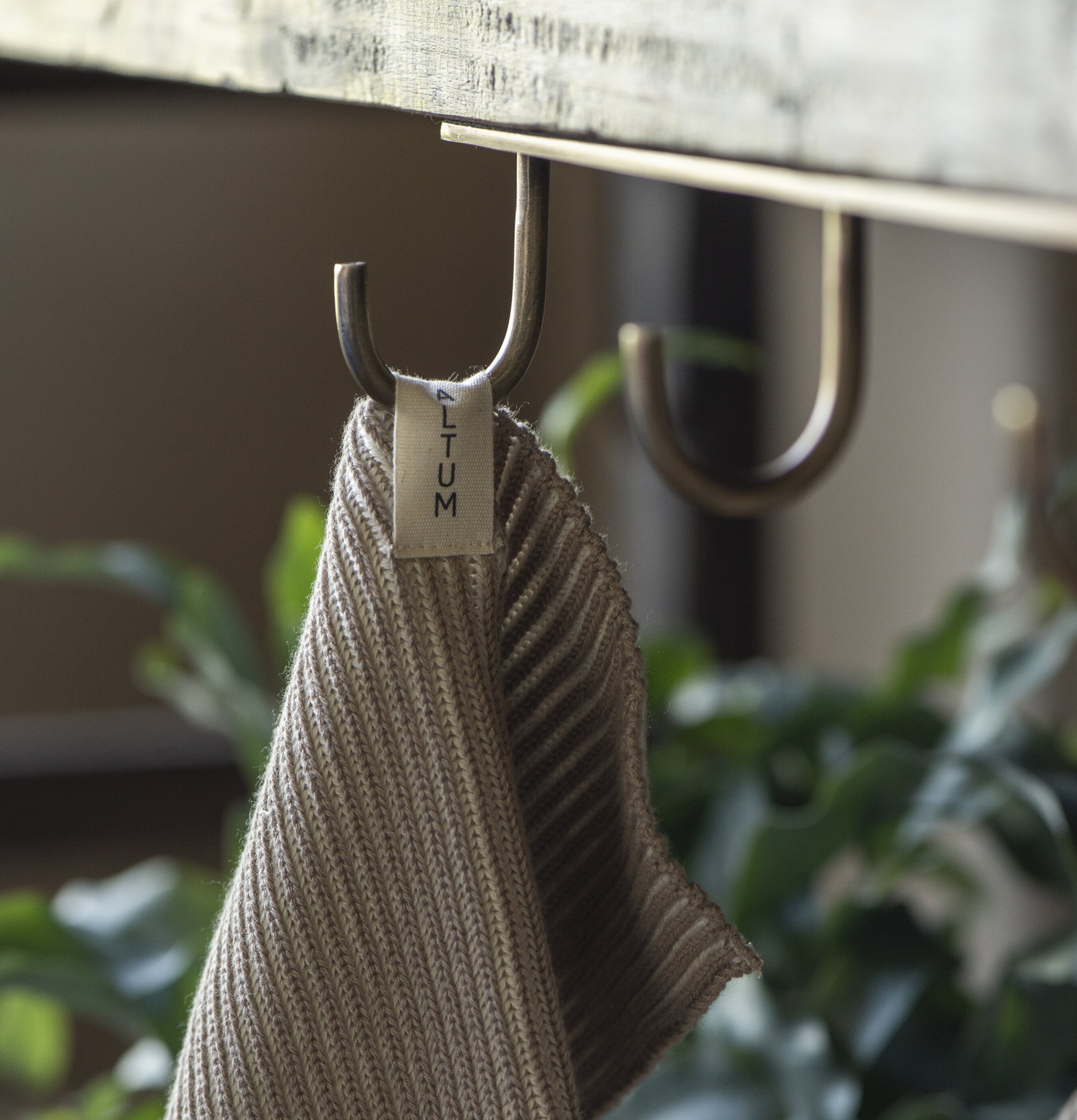 Bild av krok i antik mässing med textil och grönska