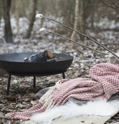 Bild av eldfat i vinterskog med textilier och marshmallows