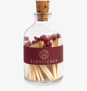 Bild av stilren glasburk med tändstickor i vinrött