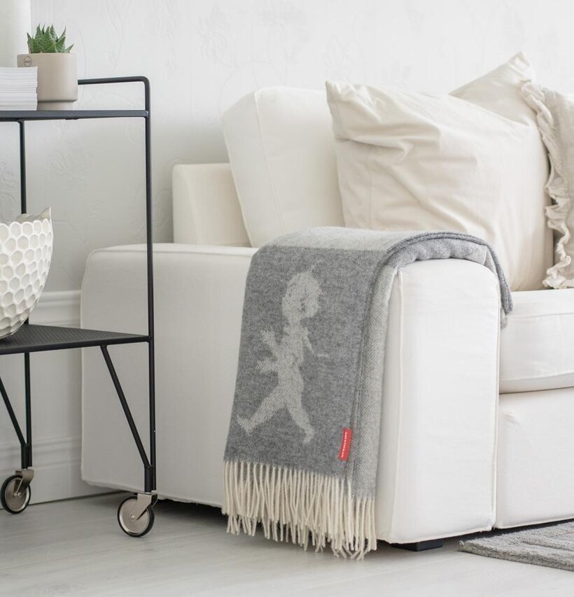 Bild av ljus inredning med grå pläd och vita kuddar