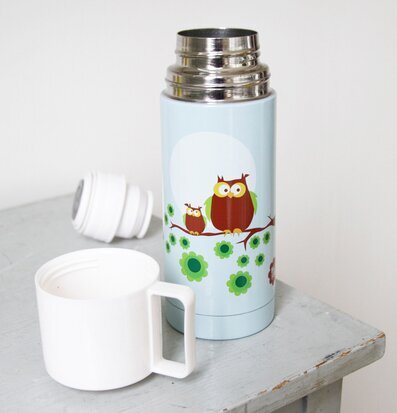 Bild av termos med ugglor och blommor på träbord