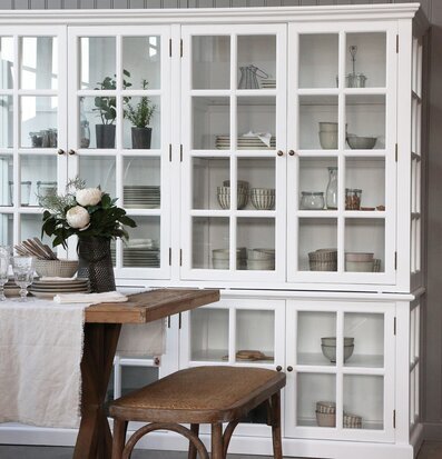 Bild av stilrent rum med vitt vitrinskåp och träbord