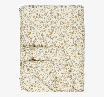 Bild av ett quiltat täcke med blommönster i cremefärg