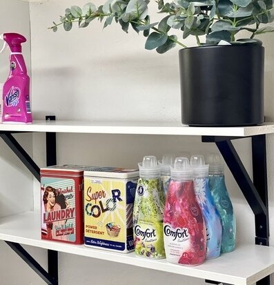 Bild av stilren hylla med städprodukter och växter