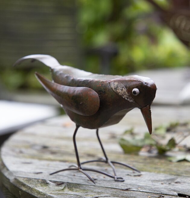 Bild av dekorativ fågel i hamrad plåt i trädgård