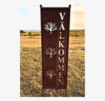 Foto av en rostig skärm med trädmotiv och texten VÄLKOMMEN