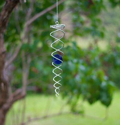 Bild av elegant vindspel med blå kula i trädgården