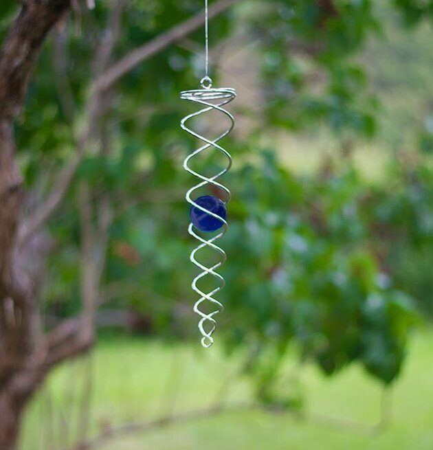 Bild av elegant vindspel med blå kula i trädgården