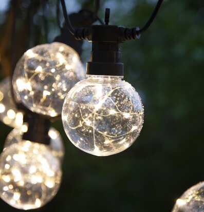 Bild av stämningsfull ljusslinga i trädgårdskväll