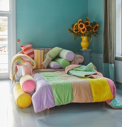 Bild av färgglatt rum med quiltad filt och solrosor