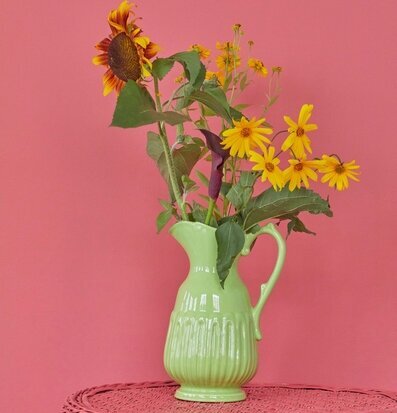 Foto av elegant keramik-kanna med blommor i fokus