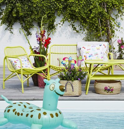 Bild av charmig uteplats med gul soffa och grön vägg