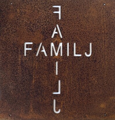 Bild av rustik skylt med ordet FAMILJ i metall