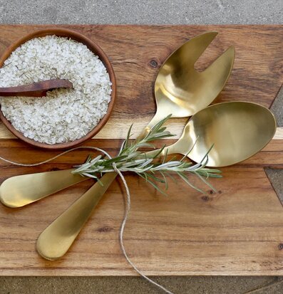 Bild av eleganta salladsbestick i guld på träbräda
