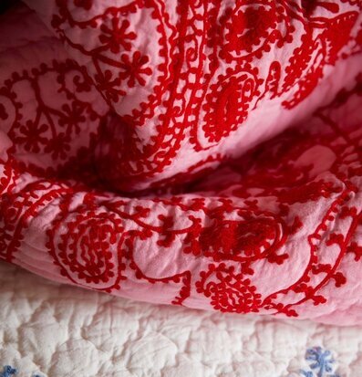 Bild av intrikat överkast med broderi i rött och blått