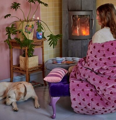 Bild av ett hemtrevligt rum med quilt och brasa