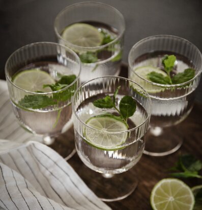 Bild av eleganta glas med lime och mynta på bricka