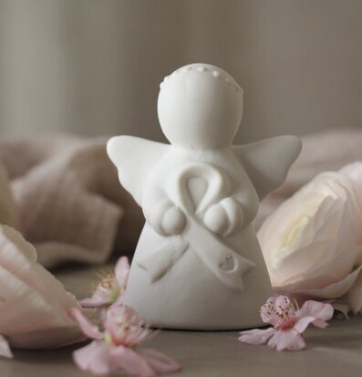 Bild av vit ängelfigur med rosa band och blommor