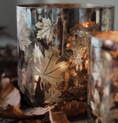 Bild av ljuslykta med höstlöv och varm belysning