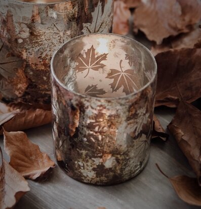 Bild av ljuslykta med höstlöv och stämningsfull atmosfär