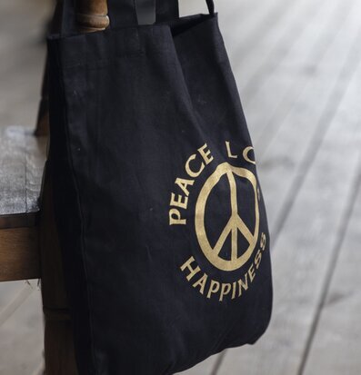 Bild av svart canvasväska med fredssymbol och text