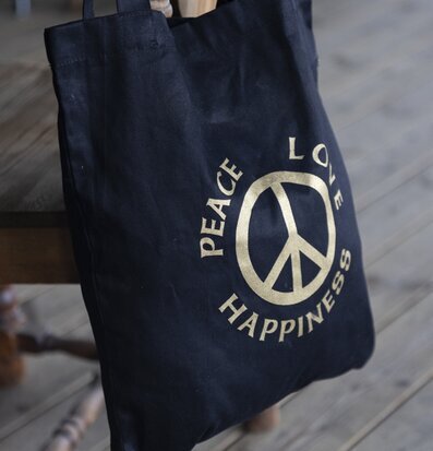 Bild av svart canvasväska med fredssymbol och text