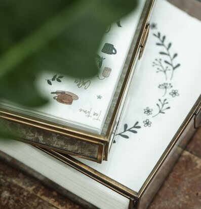 Foto av stilren glasbox med mässingsram och servetter