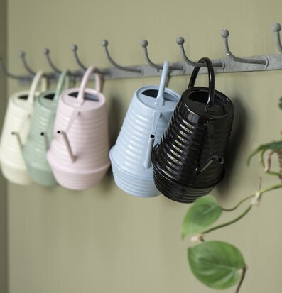 Foto av färgglada vattenkannor på grön vägg