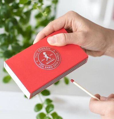 Bild av röd tändsticksask med välgörenhetsbudskap