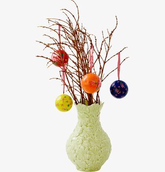 Bild av vas med kvistar och färgglada dekorationer