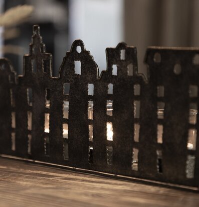 Foto av ljuslykta med stadssilhuett och hamrad plåt