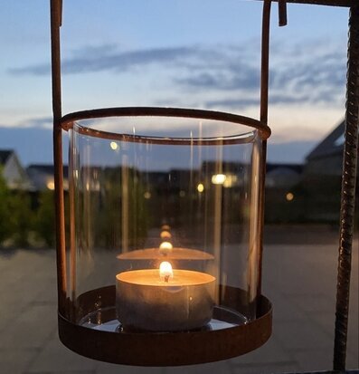 Bild av stämningsfull hängande ljusstake i trädgård