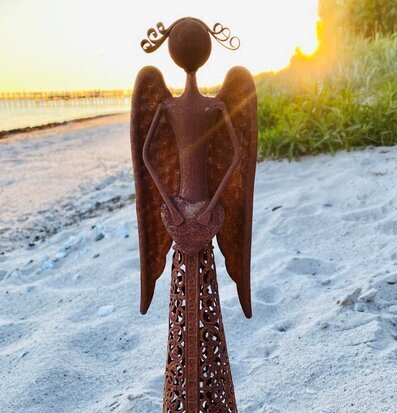 Bild av dekorativ ängel på strand i solnedgång