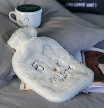 Bild av mysigt arrangemang med värmeflaska och mugg