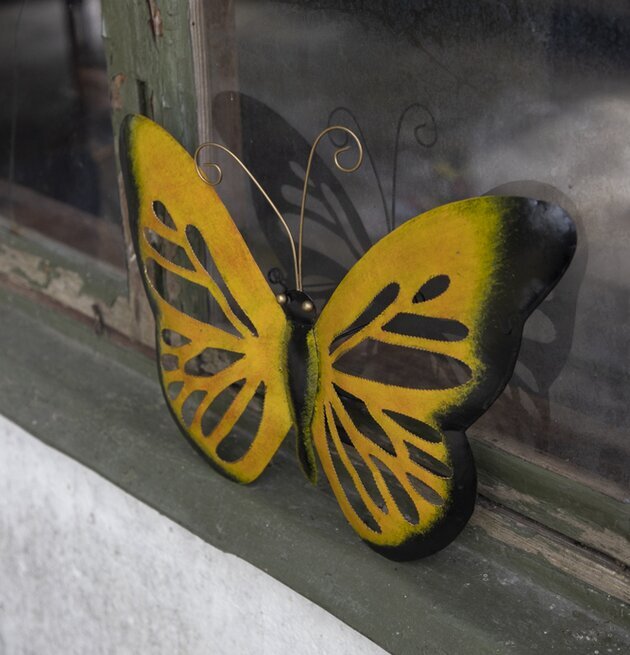 Bild av konstnärlig fjäril i hamrad plåt vid fönster
