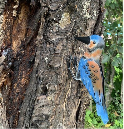 Bild av konstnärligt utformad plåtfigur i trädgård