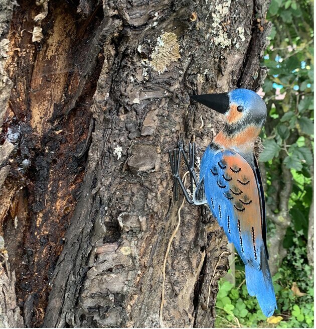 Bild av konstnärligt utformad plåtfigur i trädgård