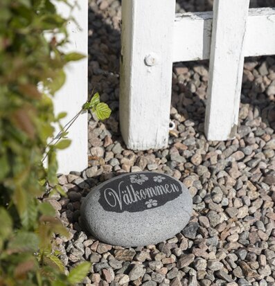 Foto av en välkomnande sten vid vit trädgårdsgrind