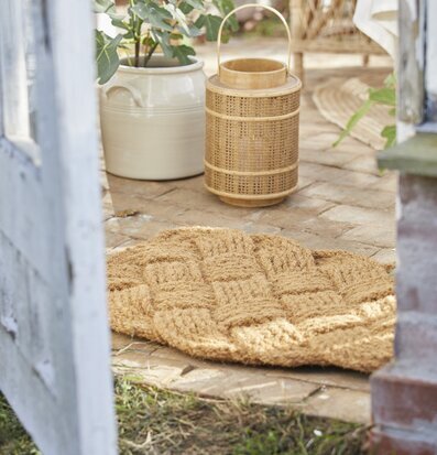 Bild av solig uteplats med dörrmatta och grönska