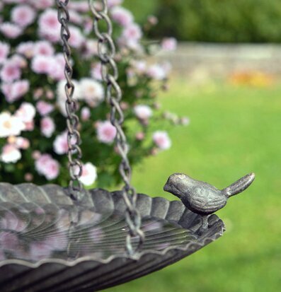 Bild av ett dekorativt fågelbad i metall i trädgård