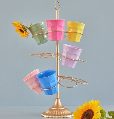 Bild av färgglada muggar på gyllene ställ med blommor