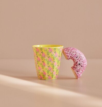 Bild av färgglad mugg och donut på beige underlag