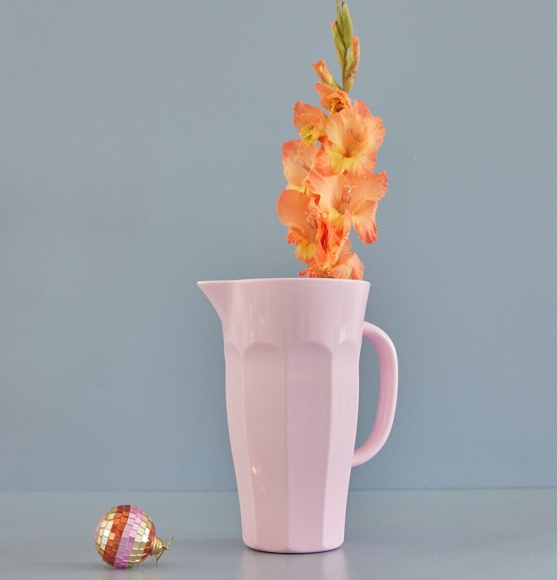 Kanna Melamin Rosa från Rice mot gråblå vägg med blomma