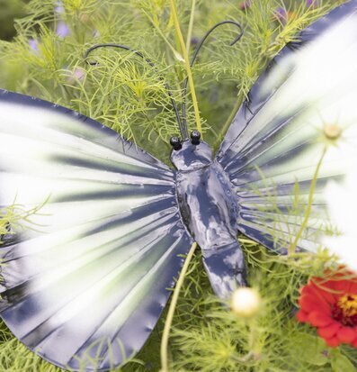 Bild av konstnärlig fjäril i hamrad plåt med blommor