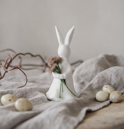 Bild av dekorativ kaninfigur med blommor och stenar