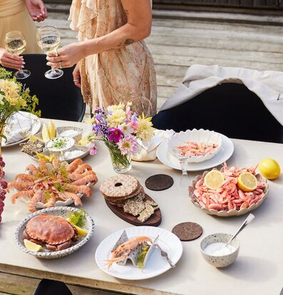 Bild av somrigt dukat bord med skaldjur och blommor