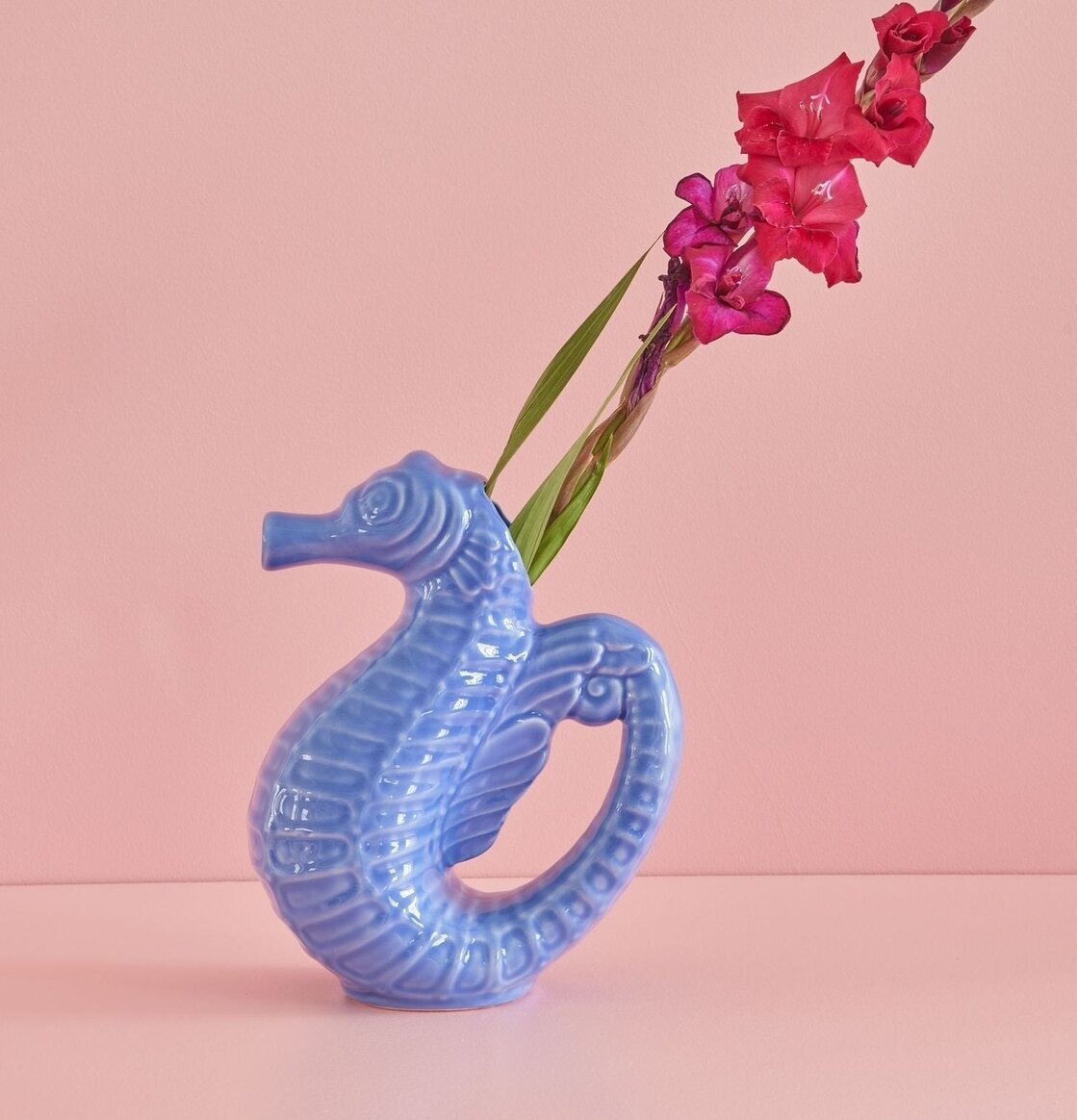 Kanna Sjöhäst Blå från Rice på rosa yta med röda blommor