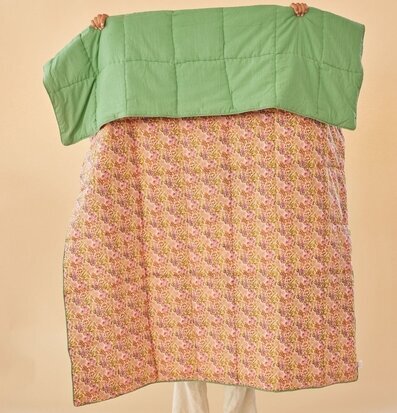 Bild av quiltat täcke med blommönster och grön topp