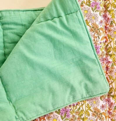 Bild av quilt med blommigt mönster och gröna toner