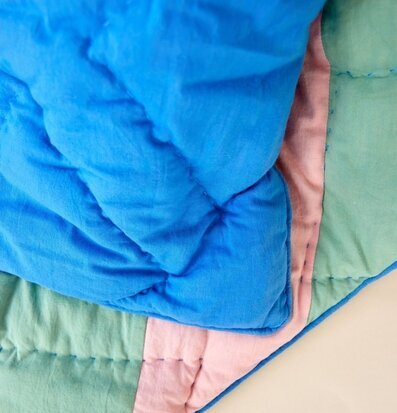 Bild av färgglatt täcke med blå, rosa och gröna toner